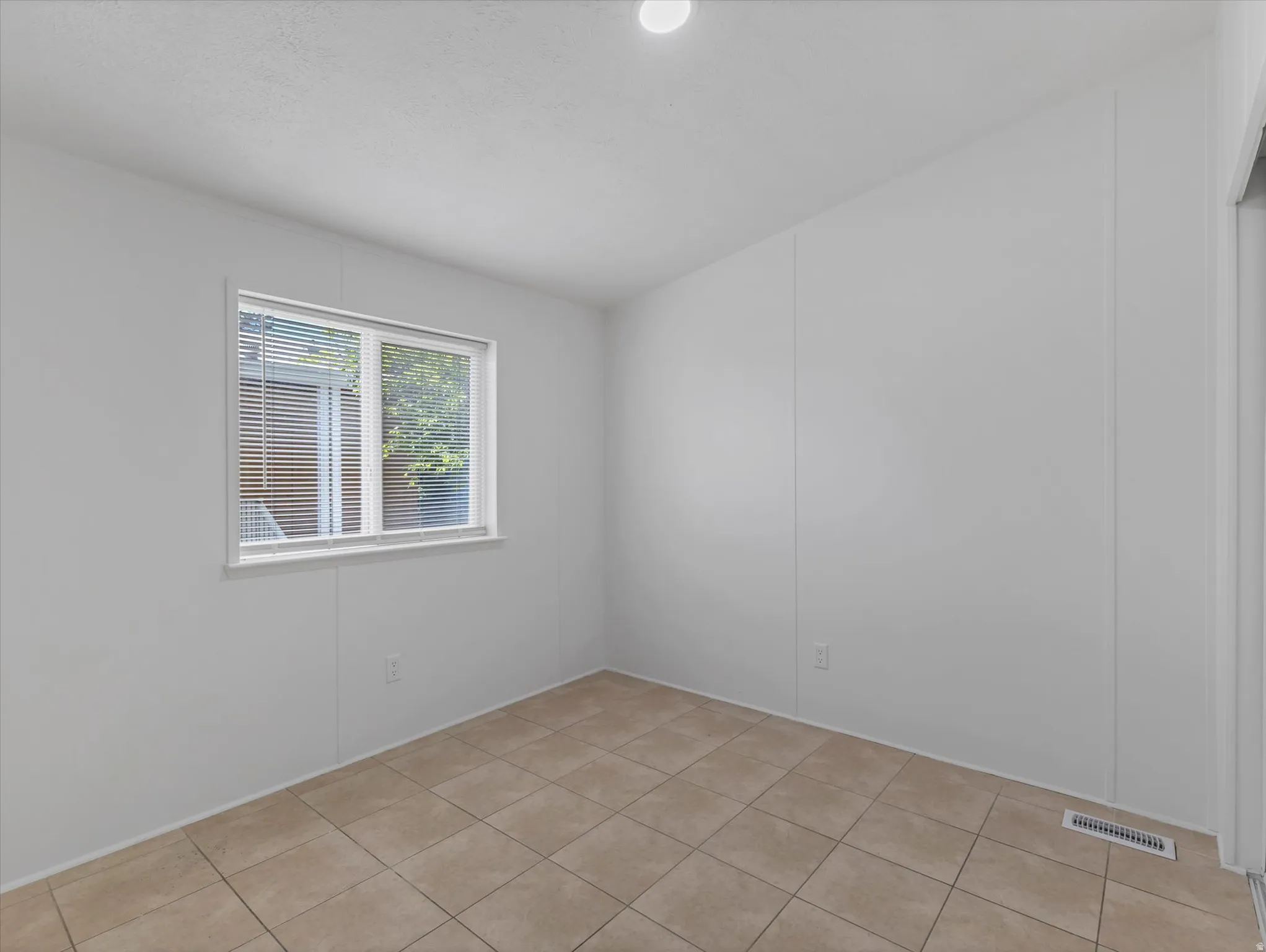 Room featuring a window with blinds, recessed ceiling light, and tile flooring