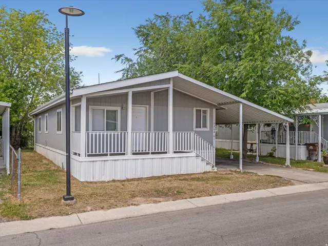 Gray siding exterior with white trim, covered front porch, integrated carport, and white railing