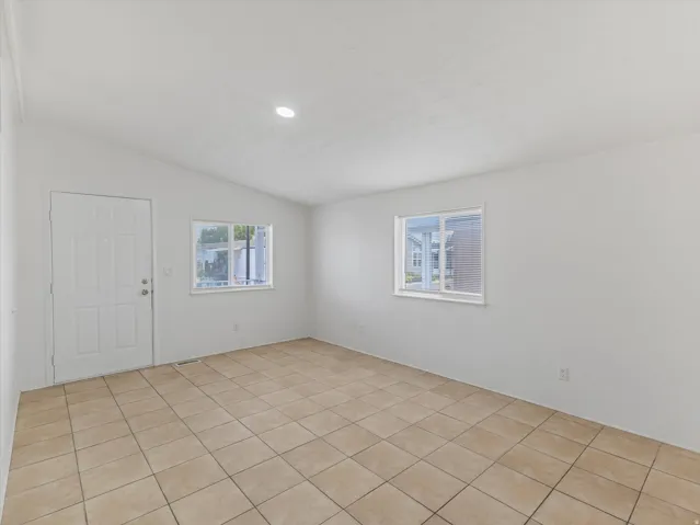 Spacious room featuring tile flooring, white walls, and multiple windows