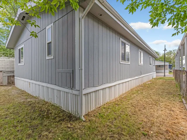 Light gray vertical siding exterior with white trim windows and a white perimeter skirt