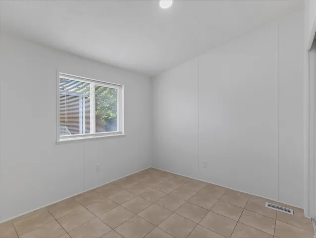 Room featuring a window with blinds, recessed ceiling light, and tile flooring