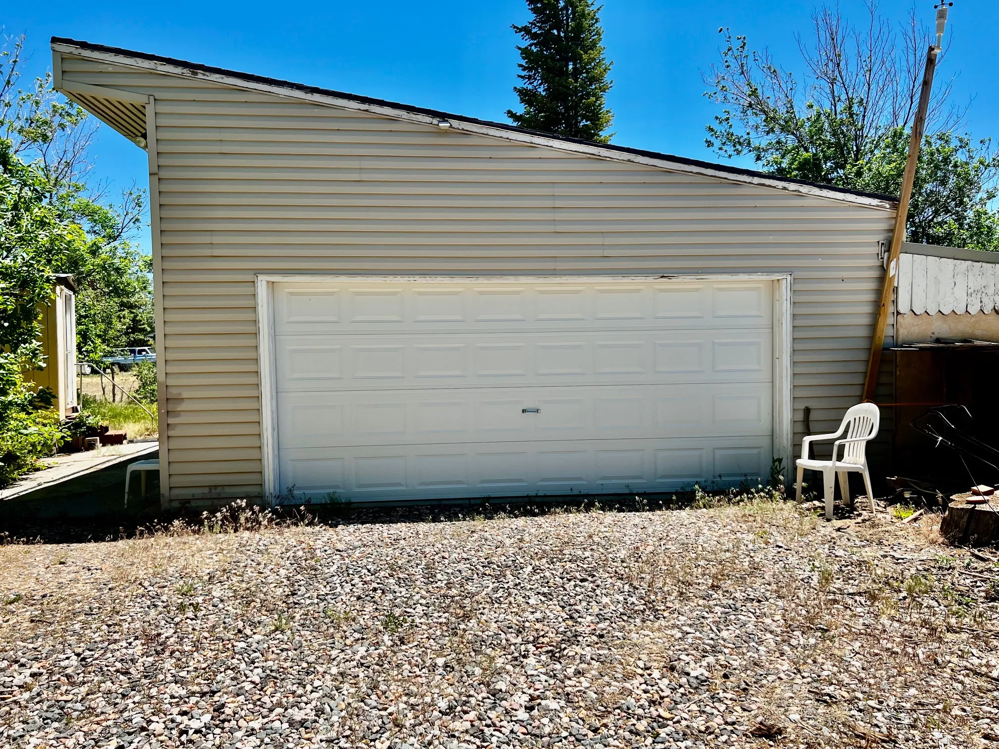 Detached garage structure featuring light-colored horizontal siding and a white paneled garage door