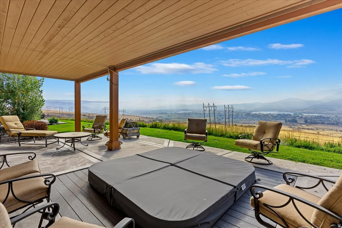Expansive covered patio featuring a hot tub, composite decking, and a concrete patio area