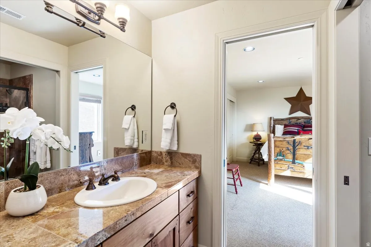 Vanity featuring a stone countertop, an undermount sink, and a bronze-finish faucet