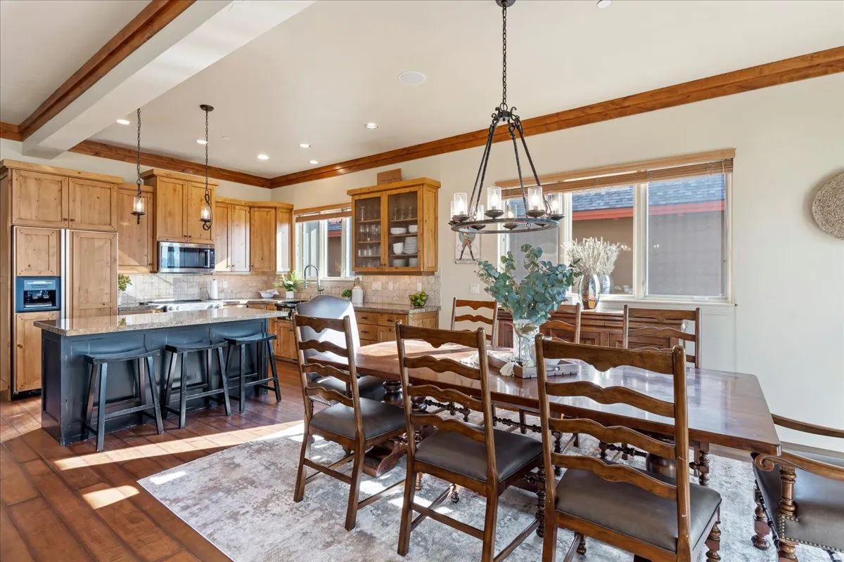 Open-concept kitchen and dining area featuring wood-finish flooring, exposed ceiling beams, and recessed lighting