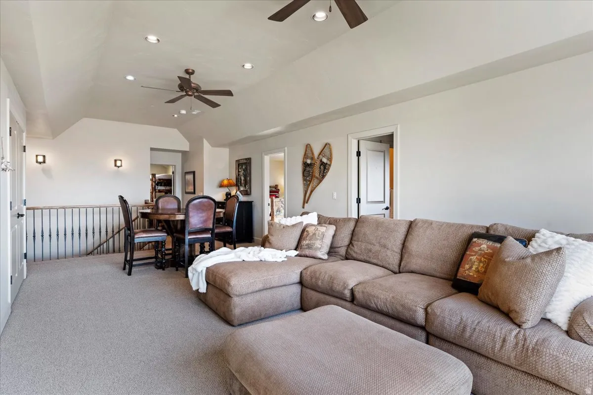 Spacious upper-level room featuring vaulted ceilings, recessed lighting, and light-colored carpeting