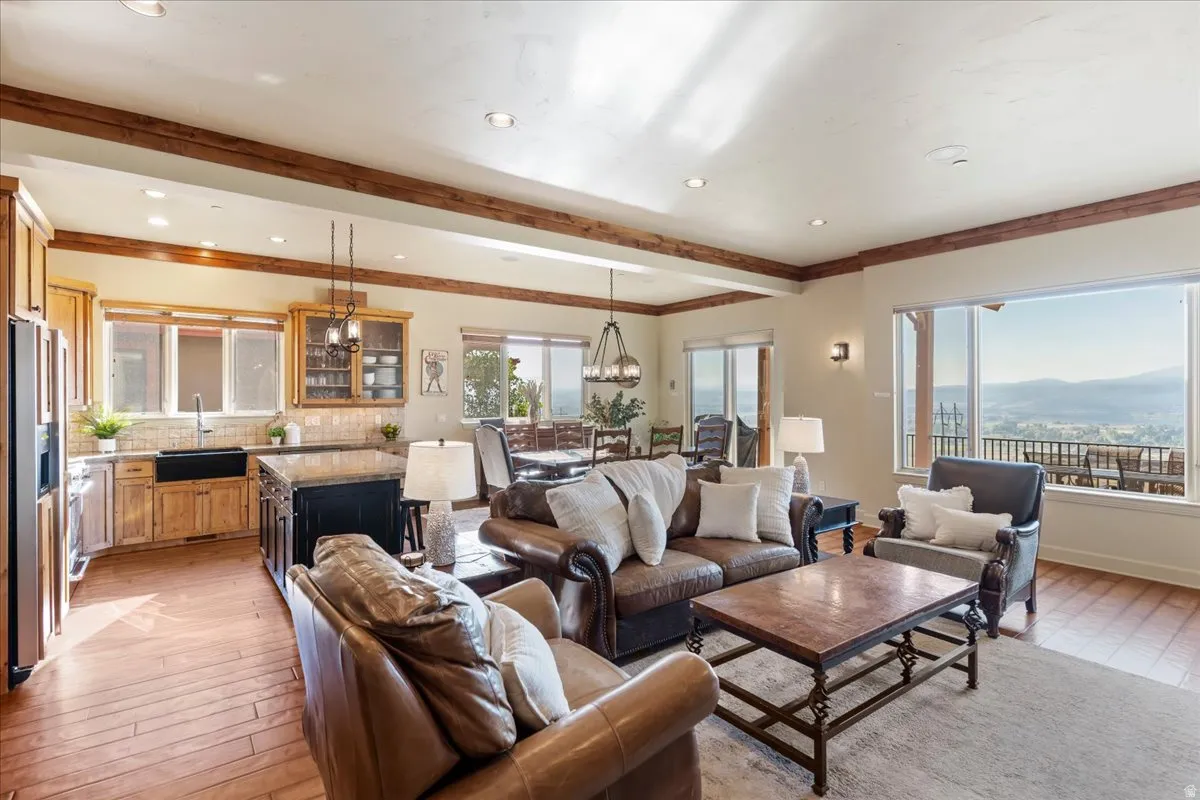 Open-concept living area with wood-finish flooring, exposed ceiling beams, recessed lighting, and expansive windows