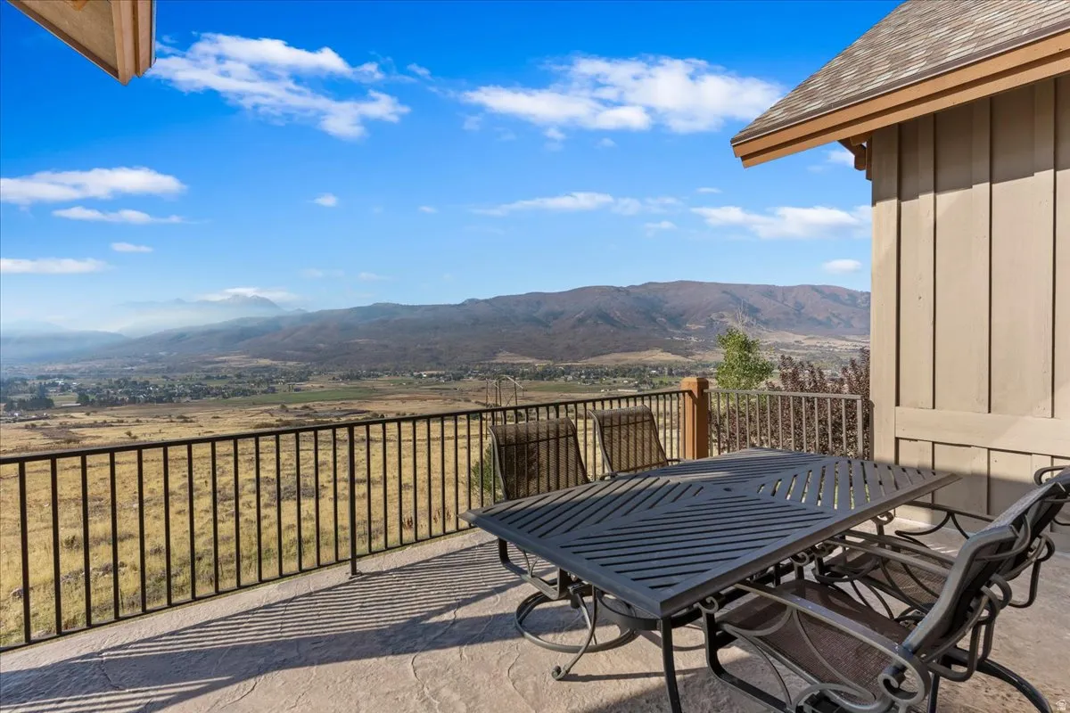 Expansive outdoor patio featuring stamped concrete flooring, dark metal railing, and a mountainous landscape