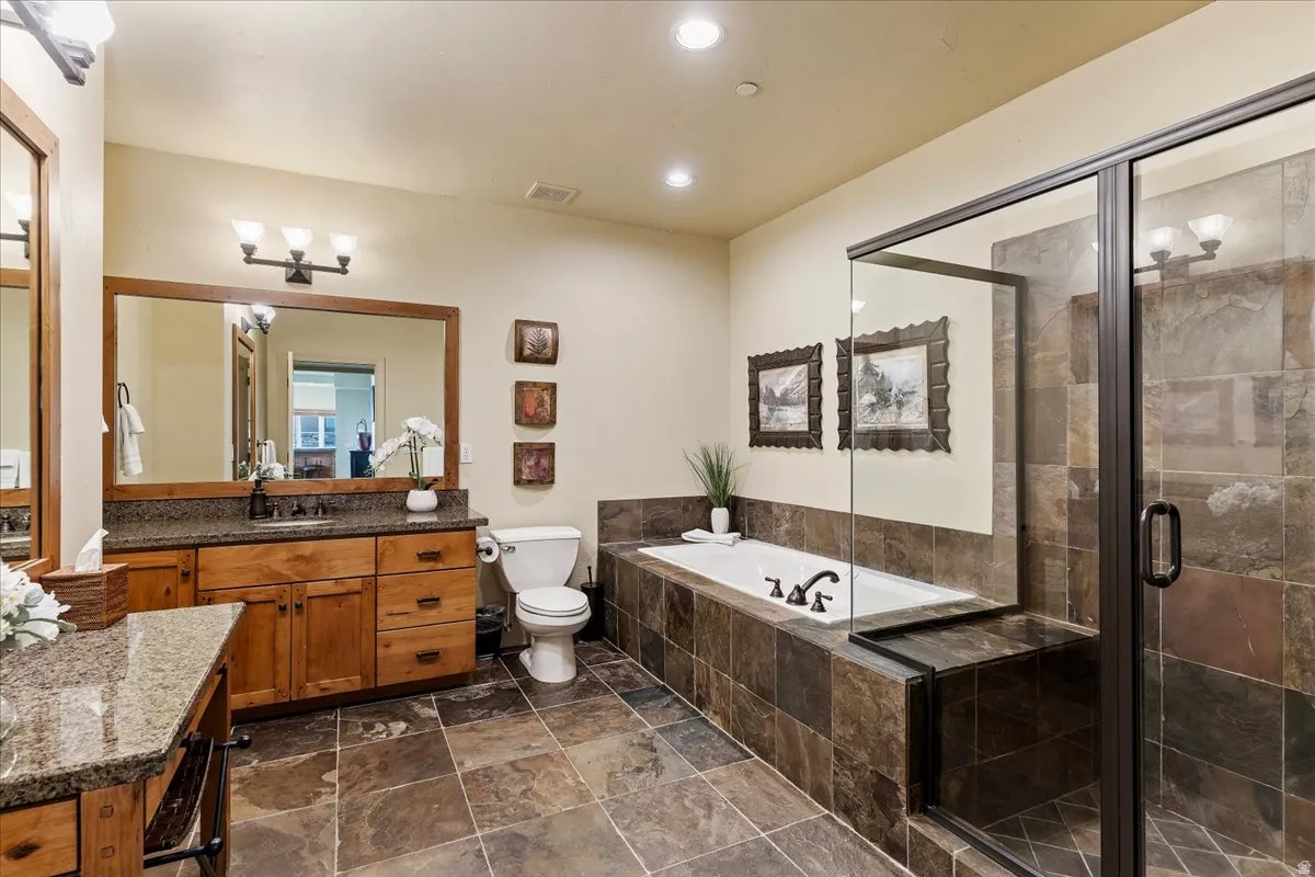 Bathroom featuring a built-in soaking tub, a walk-in shower with a glass enclosure, and a vanity with a granite-style countertop