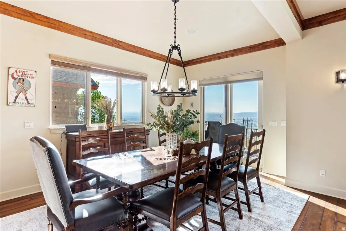 Dining area featuring wood-finish flooring, exposed ceiling beams, and a chandelier