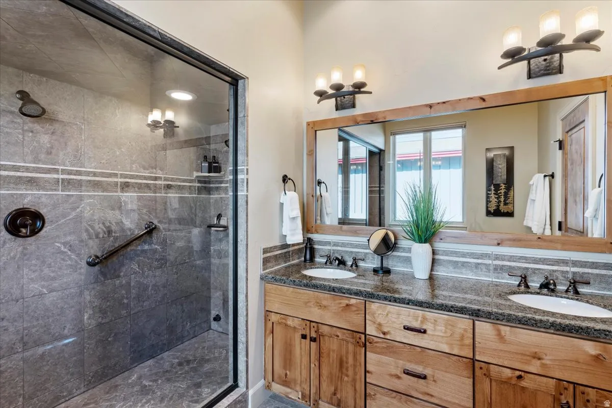 Spacious bathroom featuring a dual vanity with a granite countertop, wood-finish cabinetry, and a large framed mirror