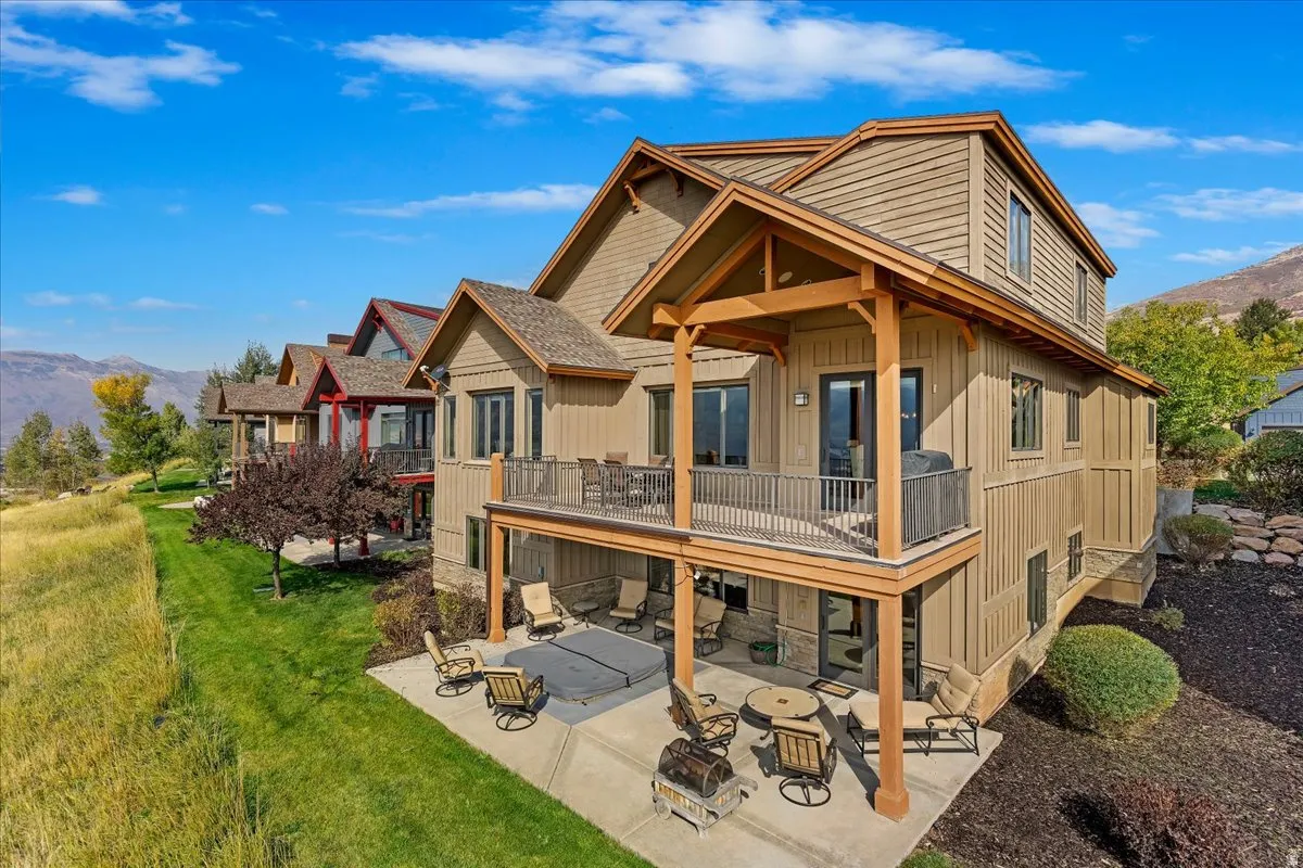 Multi-level siding exterior featuring an upper deck with metal railings and a lower patio