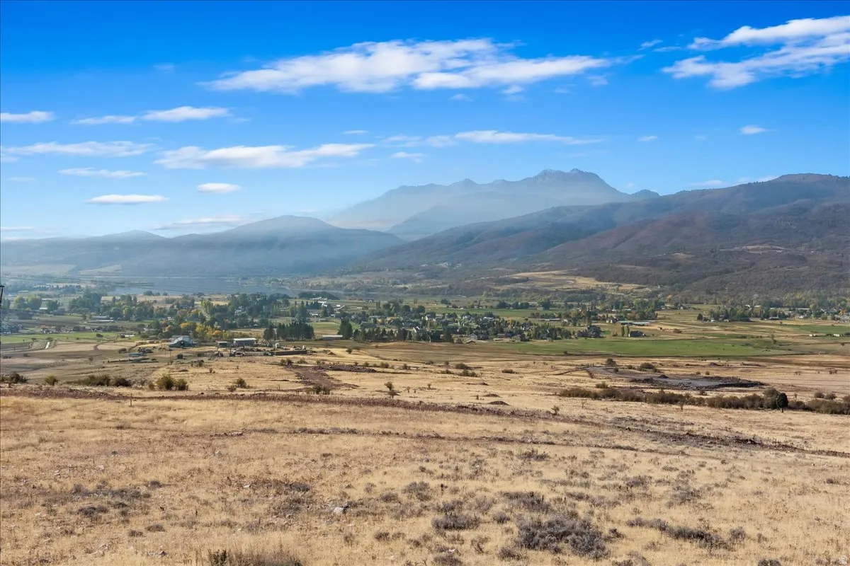 Expansive open terrain with distant mountain ranges and a small community visible in the valley
