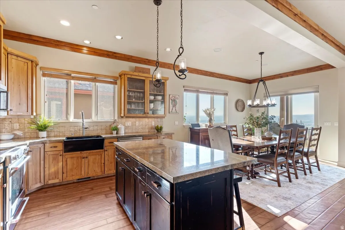 Kitchen and dining area featuring wood-finish flooring, exposed ceiling beams, and recessed lighting