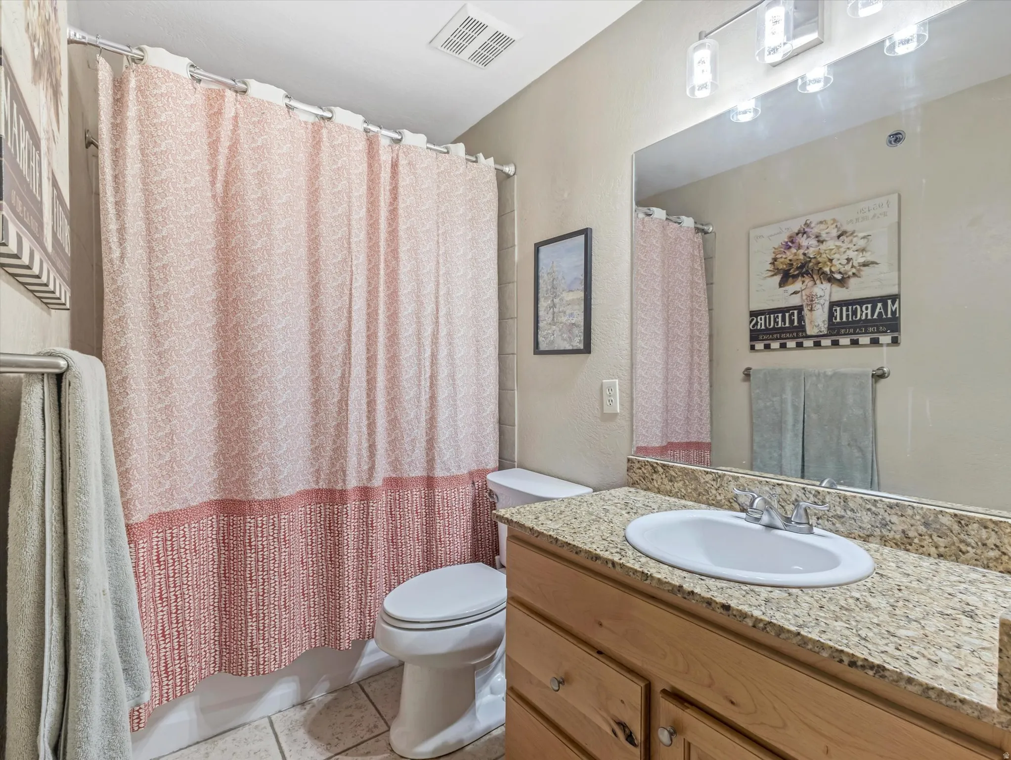 Bathroom featuring a vanity with a light-toned granite countertop, an undermount sink, and wood-finish cabinetry