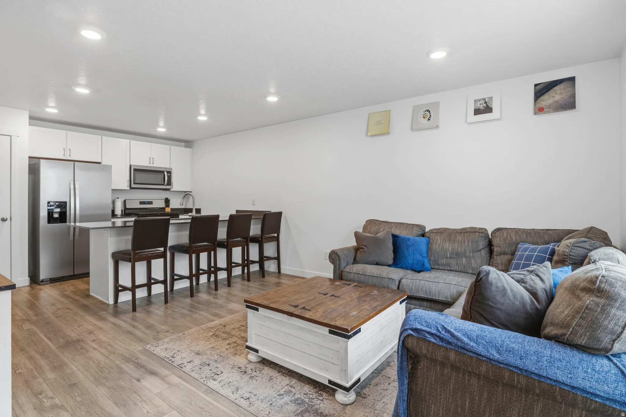 Open-concept living area featuring wood-finish flooring, recessed lighting, and a neutral color palette