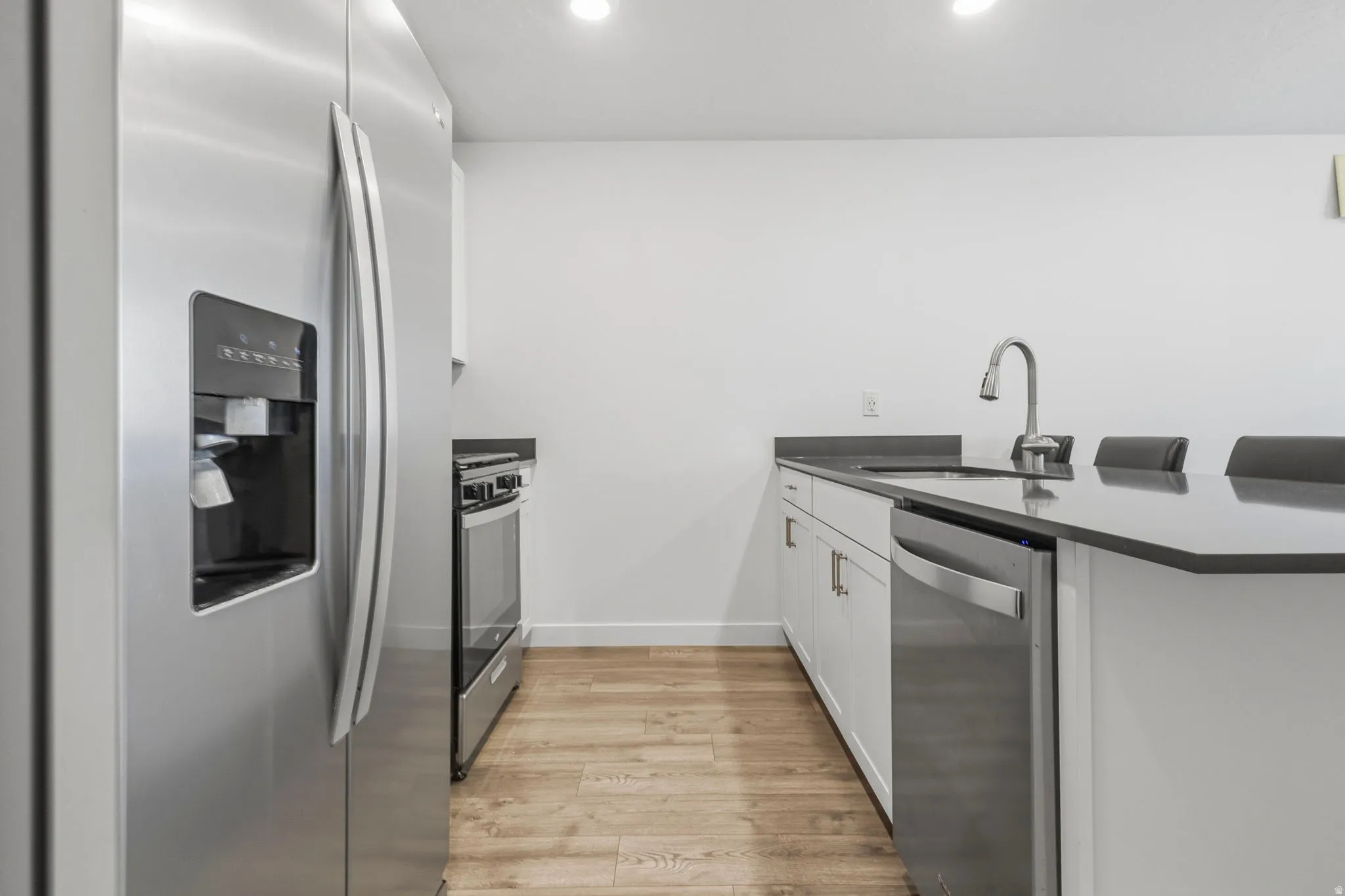 Modern kitchen featuring stainless steel appliances including a side-by-side refrigerator, range, and dishwasher