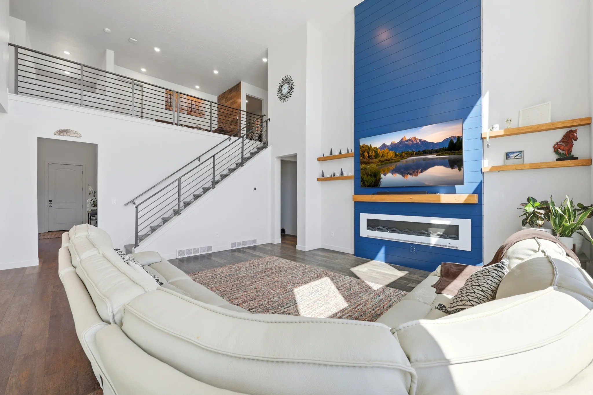 Two-story great room featuring a blue shiplap accent wall, built-in electric fireplace, recessed lighting, and wood-finish flooring