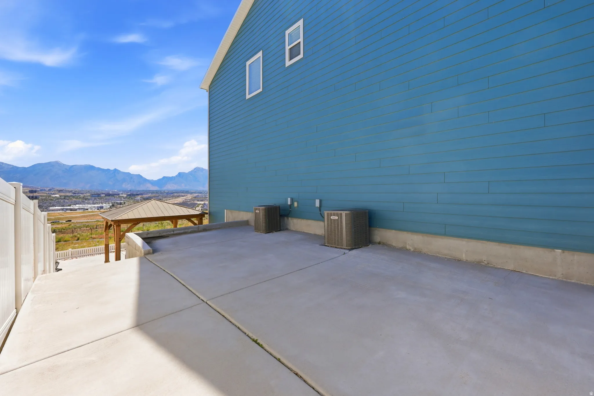Expansive concrete patio area with a white privacy fence