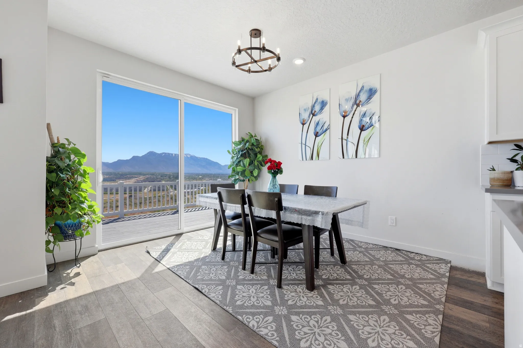 Spacious dining area featuring wood-finish flooring, a contemporary chandelier, and white walls