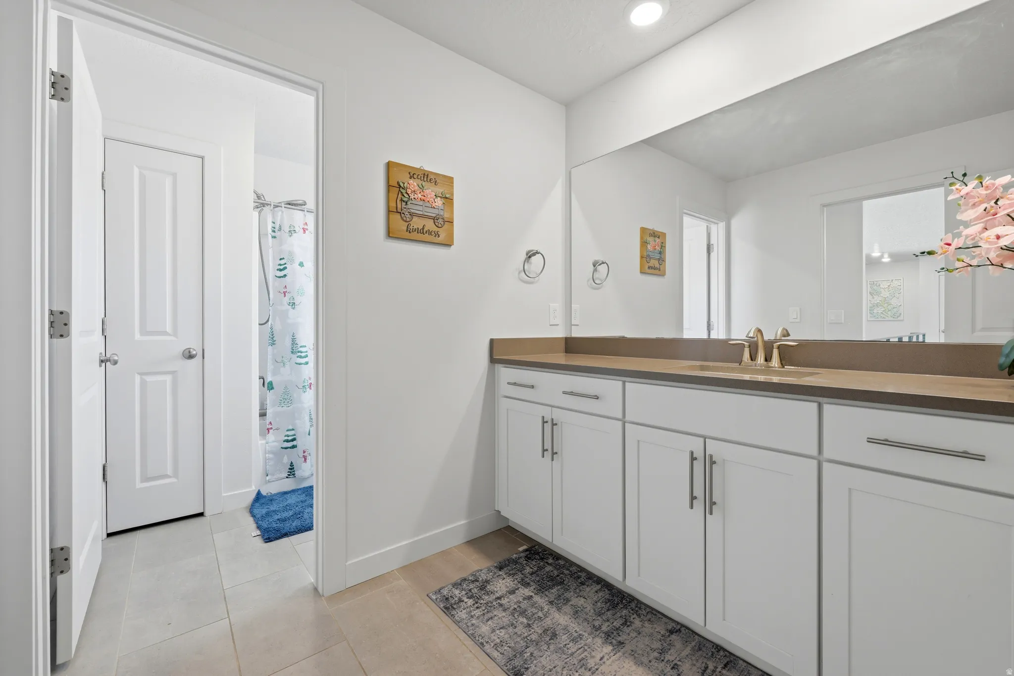 Bathroom featuring an extended vanity with white cabinetry, a large wall-mounted mirror, brushed brass fixtures, and recessed lighting