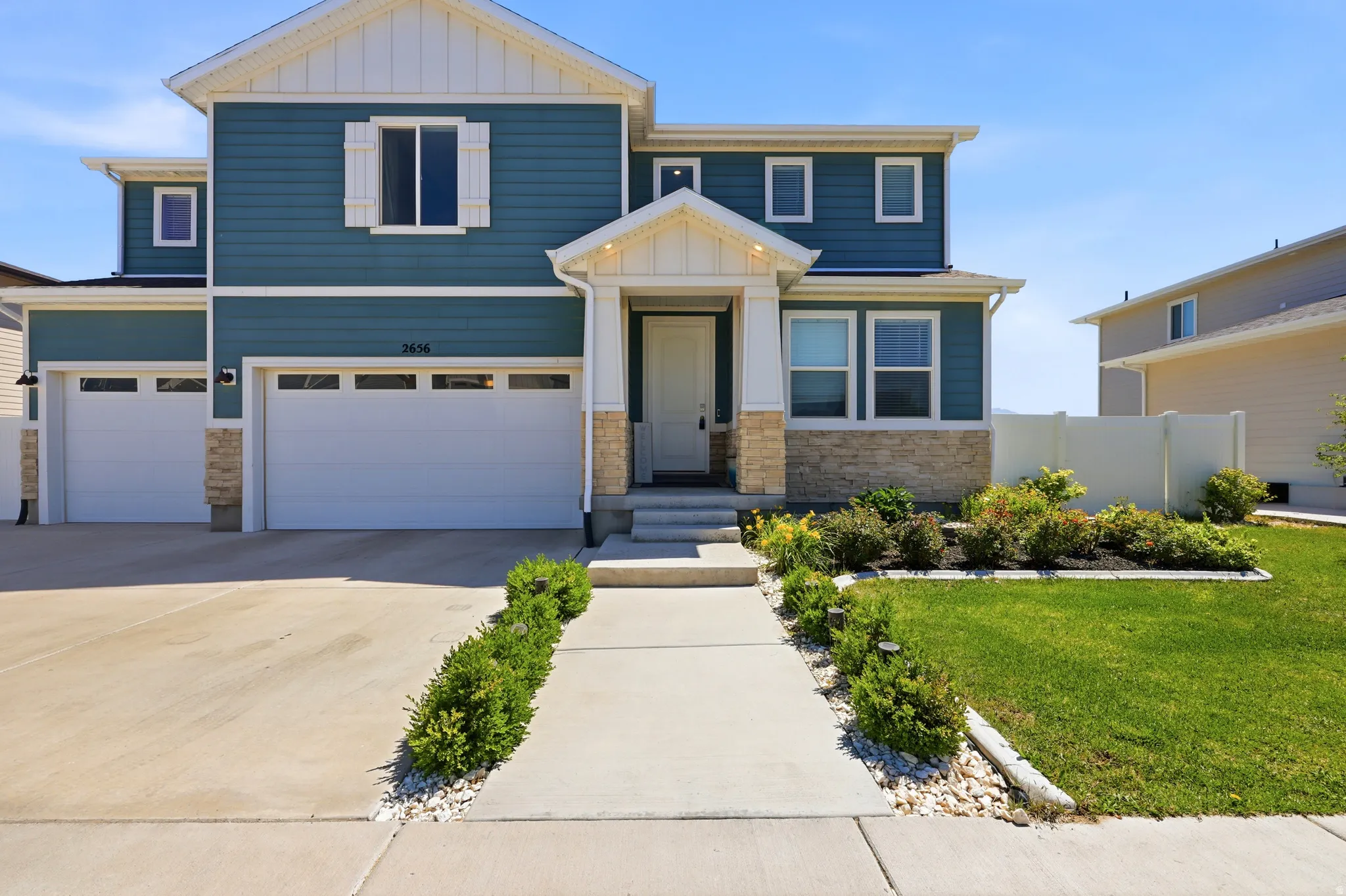 Contemporary two-story exterior featuring blue siding, white trim, and stone accents