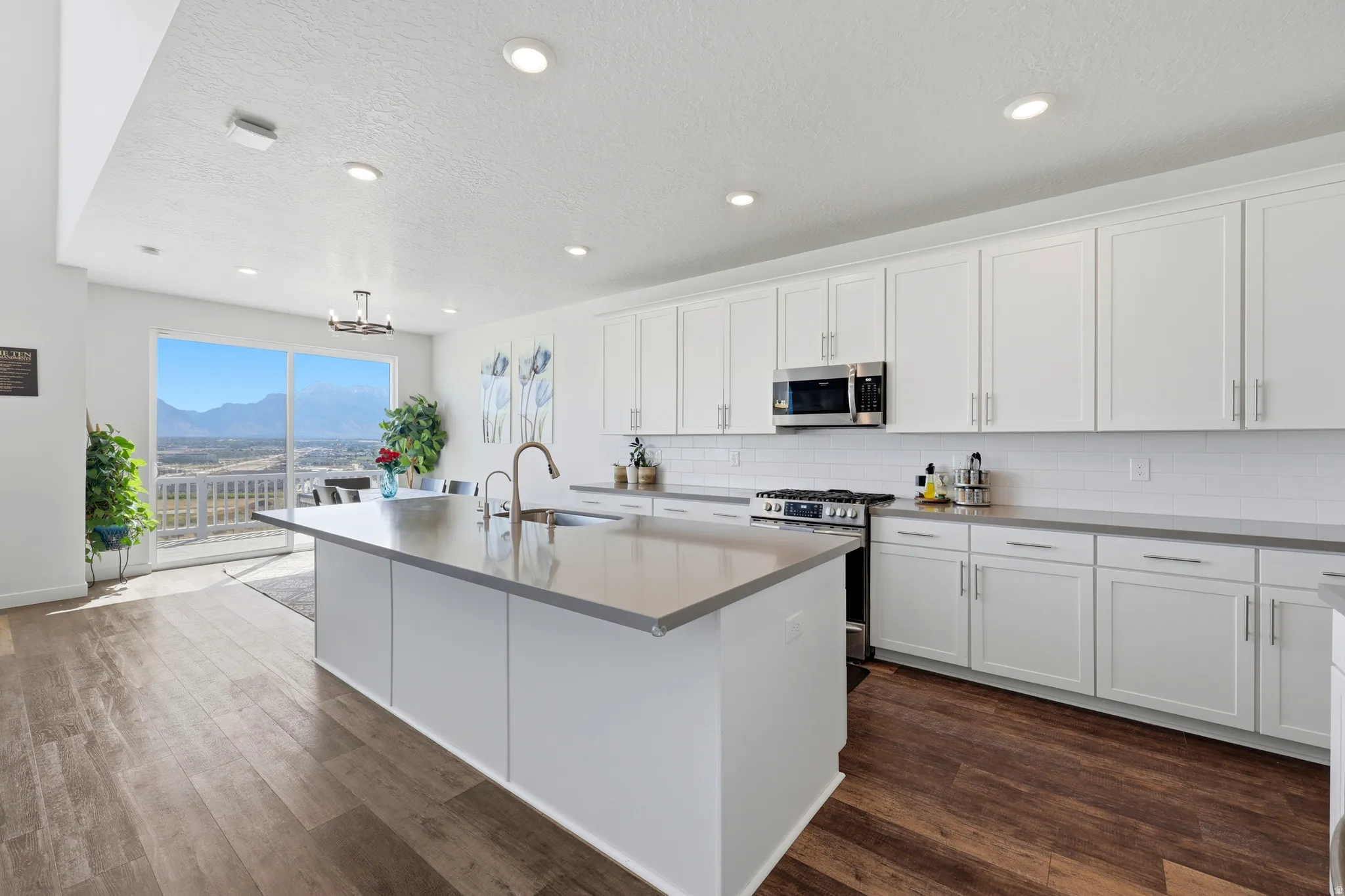 Modern kitchen featuring an expansive center island, white shaker-style cabinetry, and light gray countertops