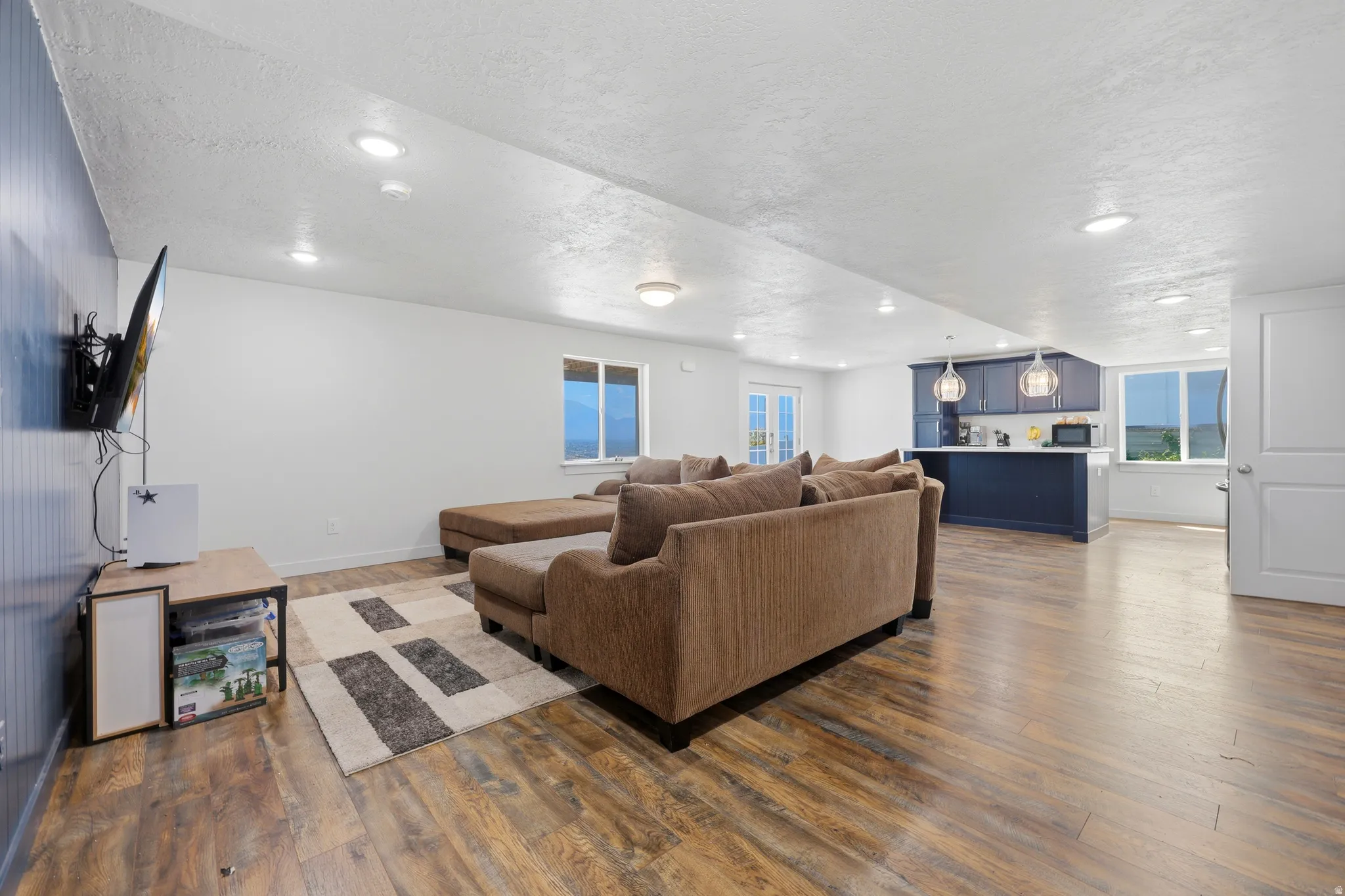 Open-concept living area featuring wood-finish flooring, recessed lighting, and a kitchen with dark cabinetry