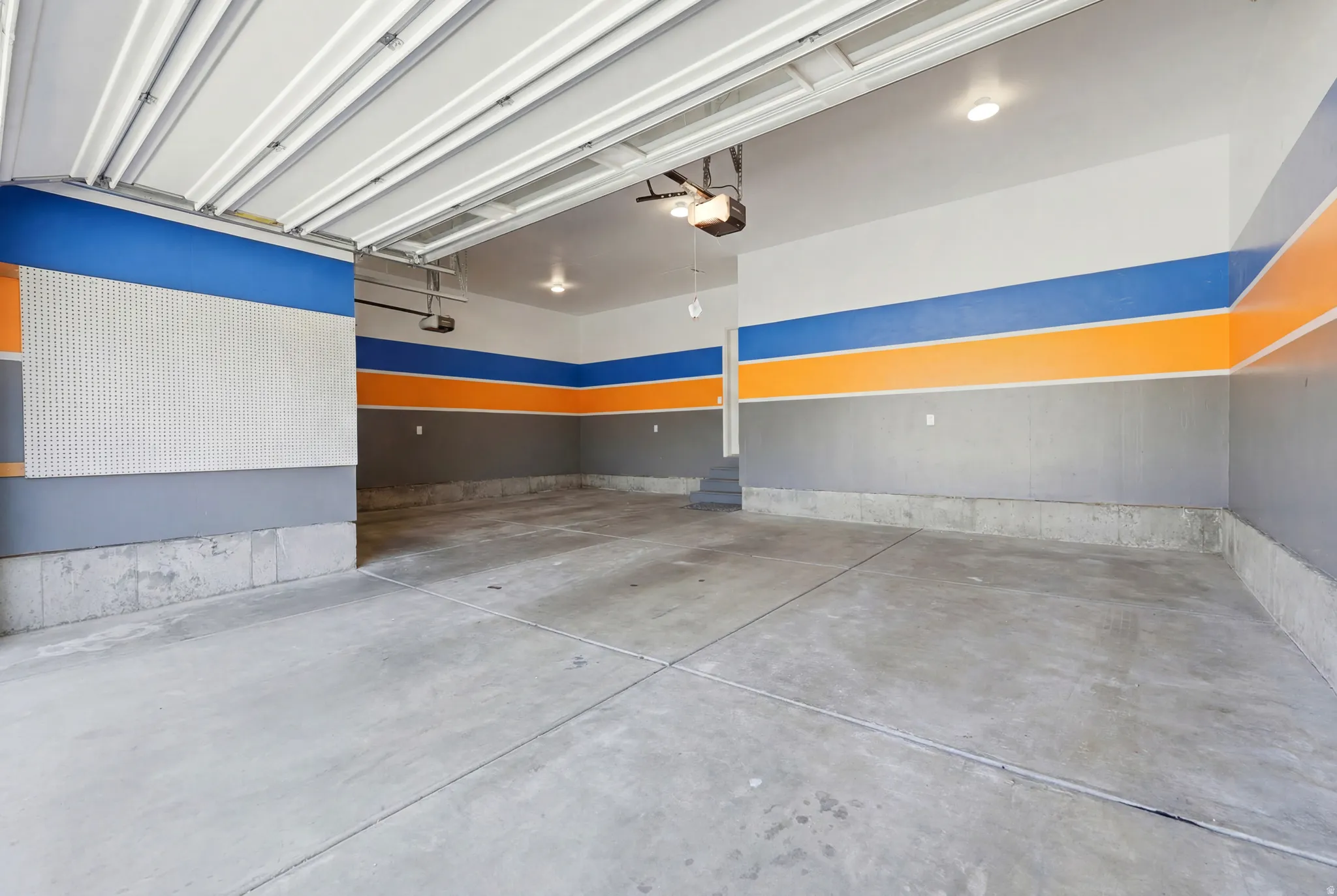 Spacious garage featuring a concrete floor, painted accent walls, overhead lighting, and an automatic garage door opener