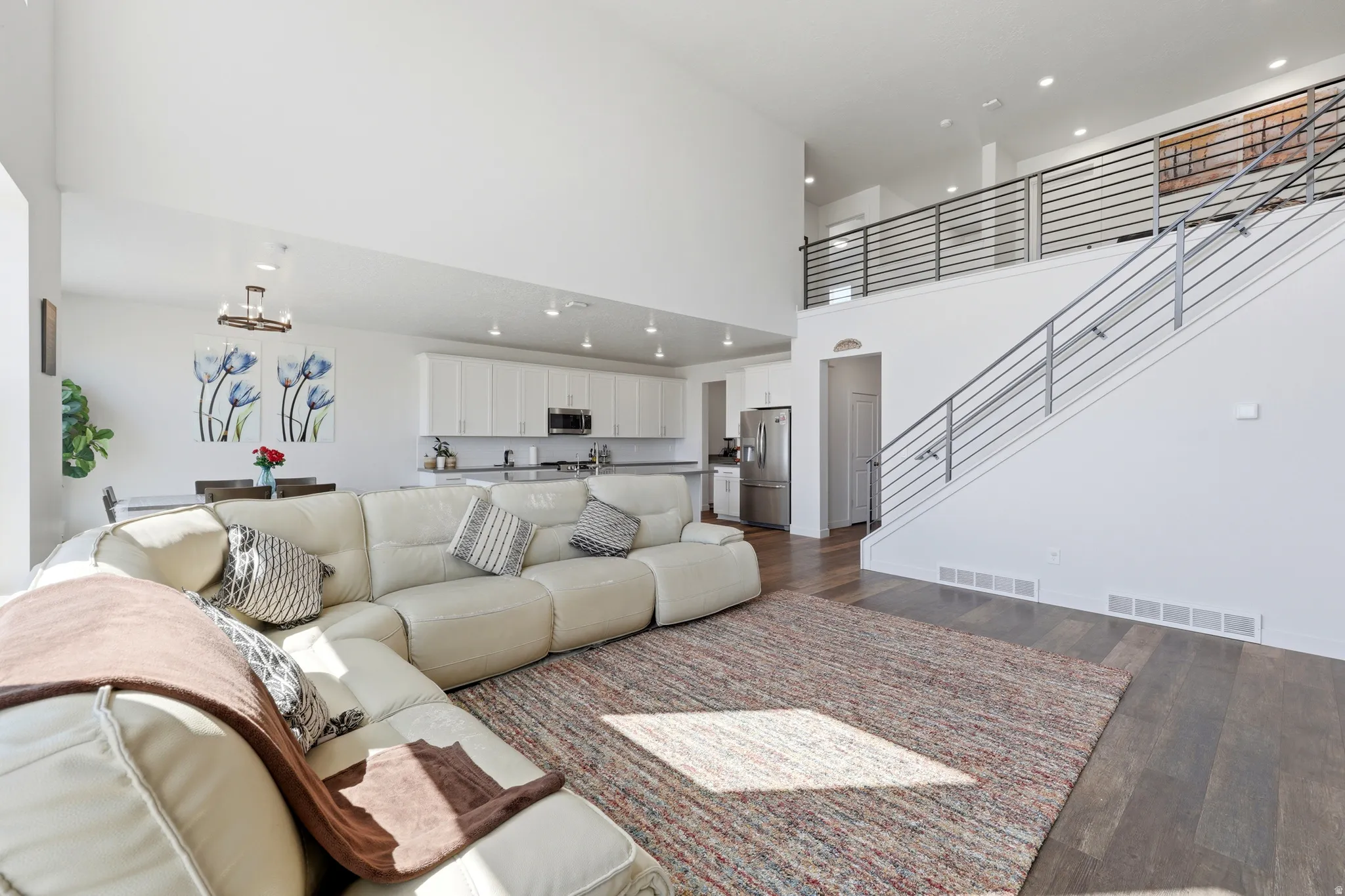 Open-concept living area featuring a vaulted ceiling, wood-finish flooring, and a modern stair railing
