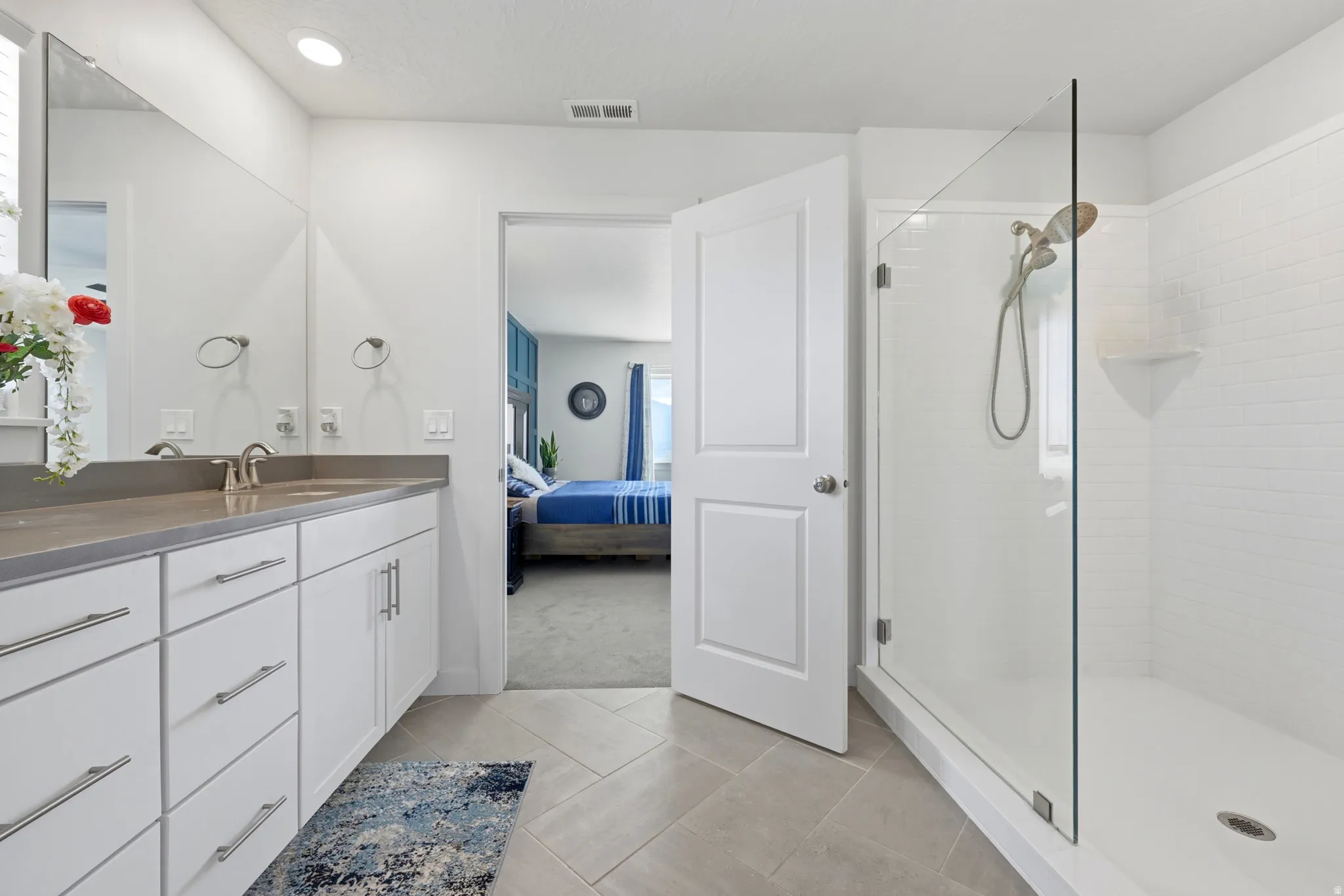 Bathroom featuring a dual-sink vanity with white cabinetry and a solid surface countertop