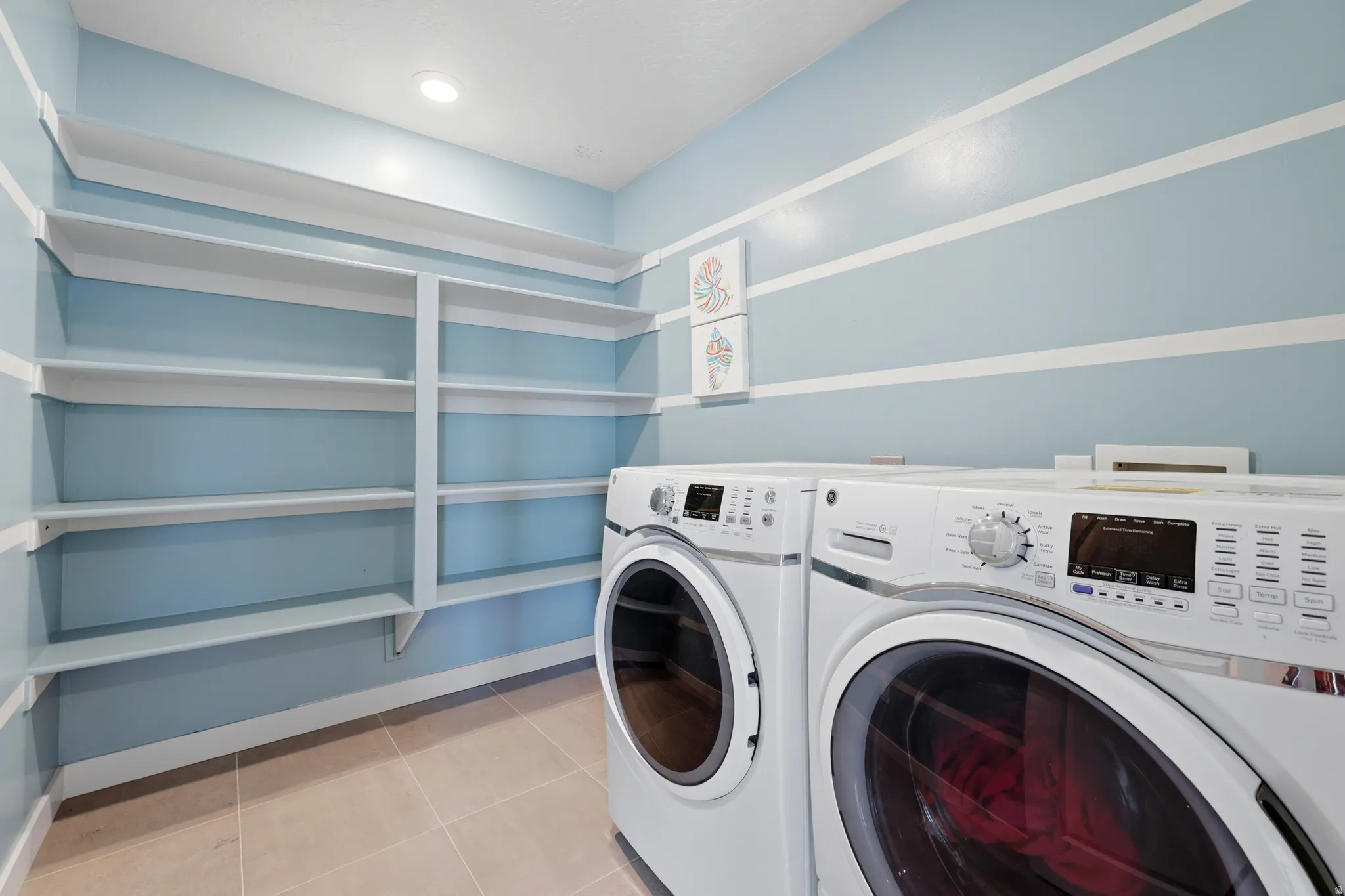 Dedicated utility room featuring ample built-in shelving, durable tile flooring, recessed ceiling lighting, and a neutral color palette