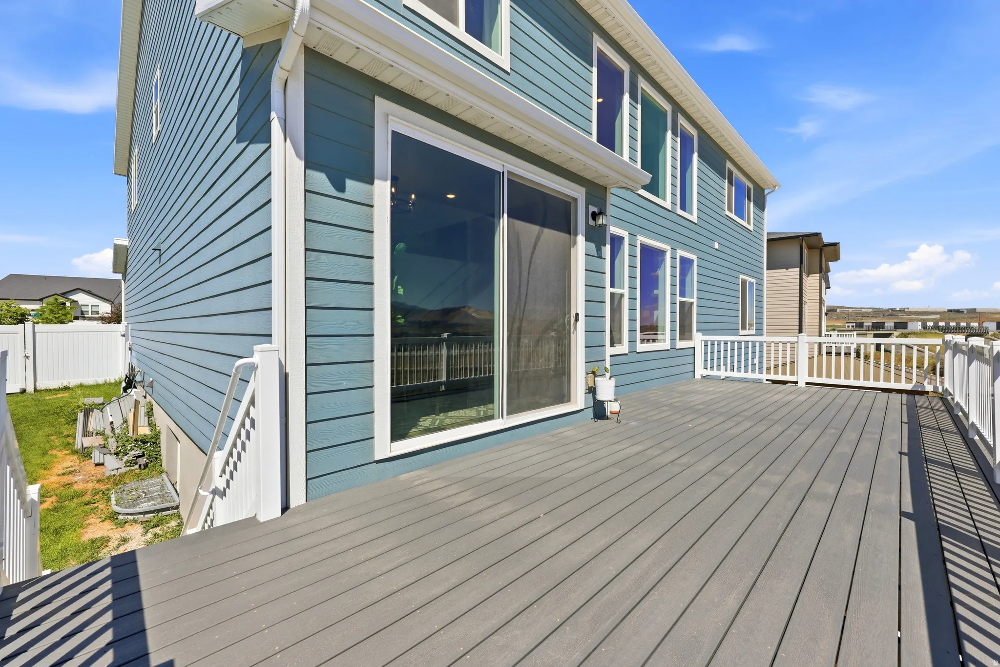 Spacious exterior deck with composite flooring, white railing, and sliding glass door access