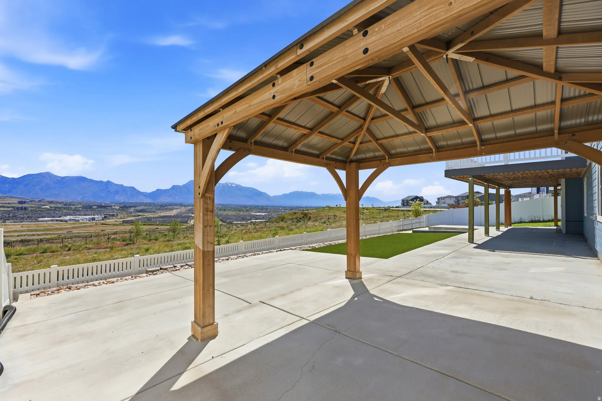Expansive concrete patio featuring a substantial wood-frame gazebo with a corrugated metal roof