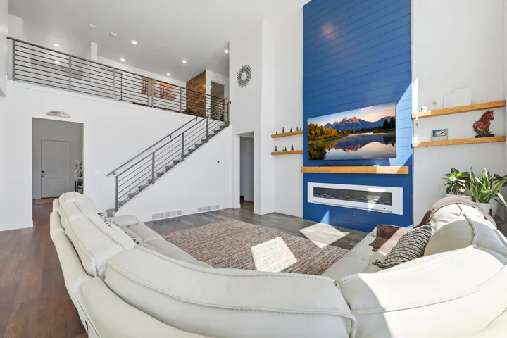 Two-story great room featuring a blue shiplap accent wall, built-in electric fireplace, recessed lighting, and wood-finish flooring
