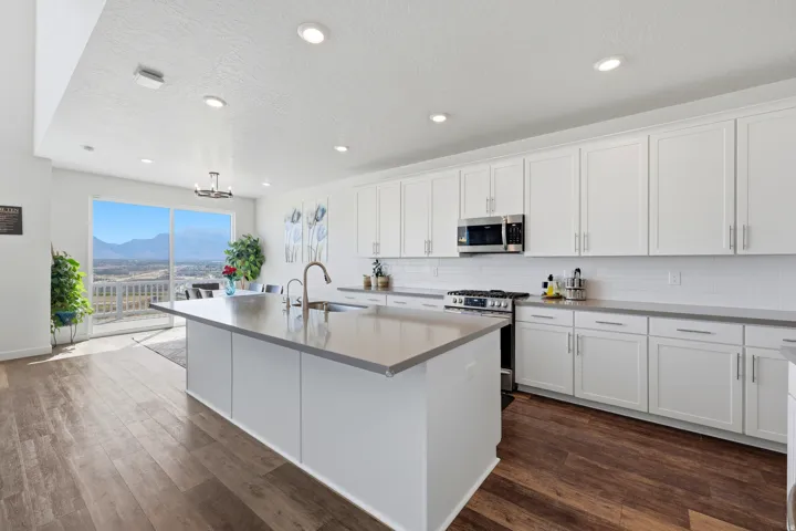 Modern kitchen featuring an expansive center island, white shaker-style cabinetry, and light gray countertops