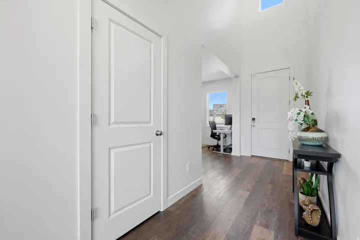 Foyer featuring wood-finish flooring, white paneled doors, and high ceilings with upper windows