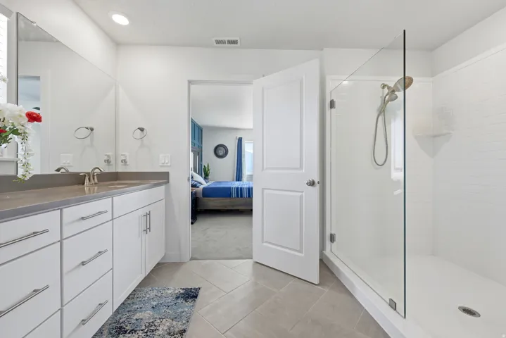 Bathroom featuring a dual-sink vanity with white cabinetry and a solid surface countertop