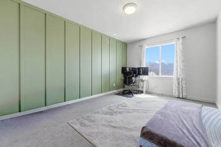 Expansive room featuring a striking accent wall with vertical paneling, plush carpeting, and a large window offering mountain scenery