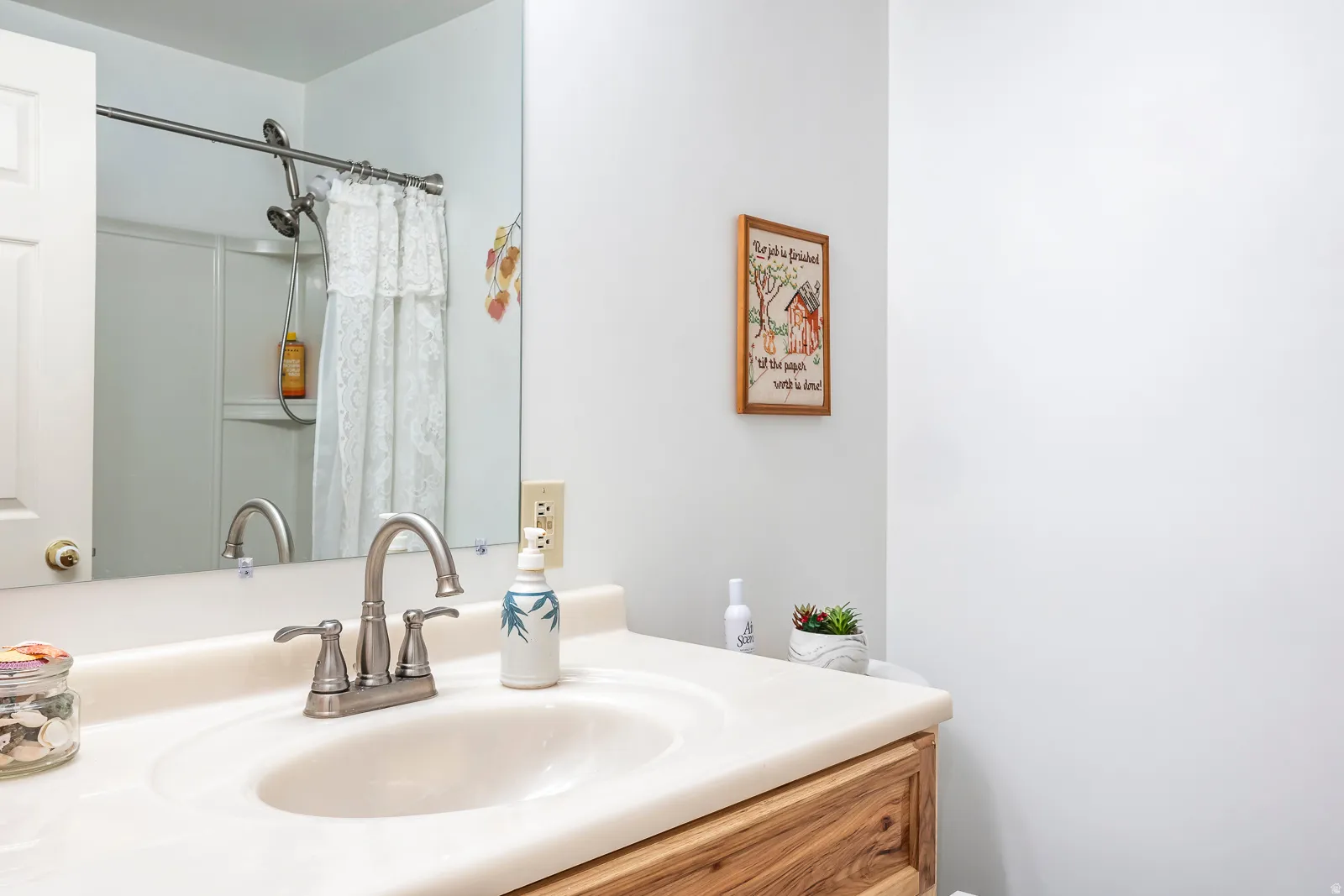 Bathroom vanity featuring a light-toned countertop, integrated sink, and brushed nickel faucet