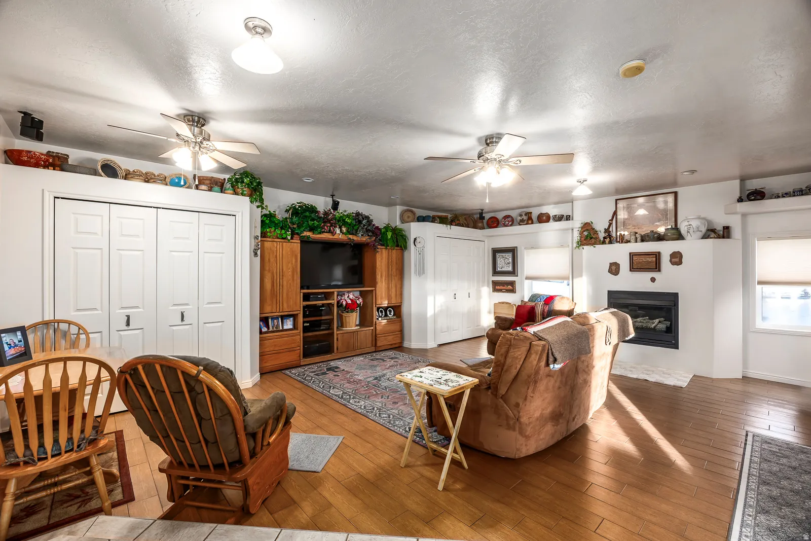 Spacious interior featuring wood-finish flooring, a built-in entertainment center, and a white fireplace surround
