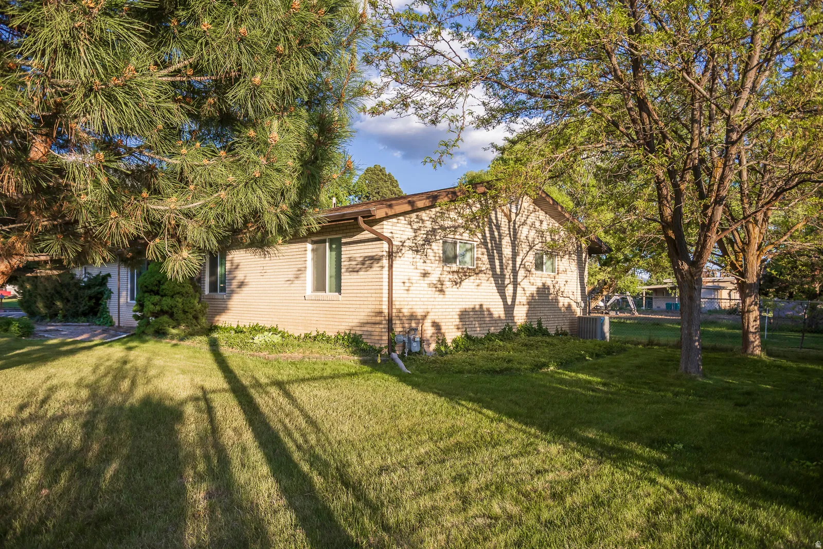 Expansive lawn area featuring mature trees and a brick exterior