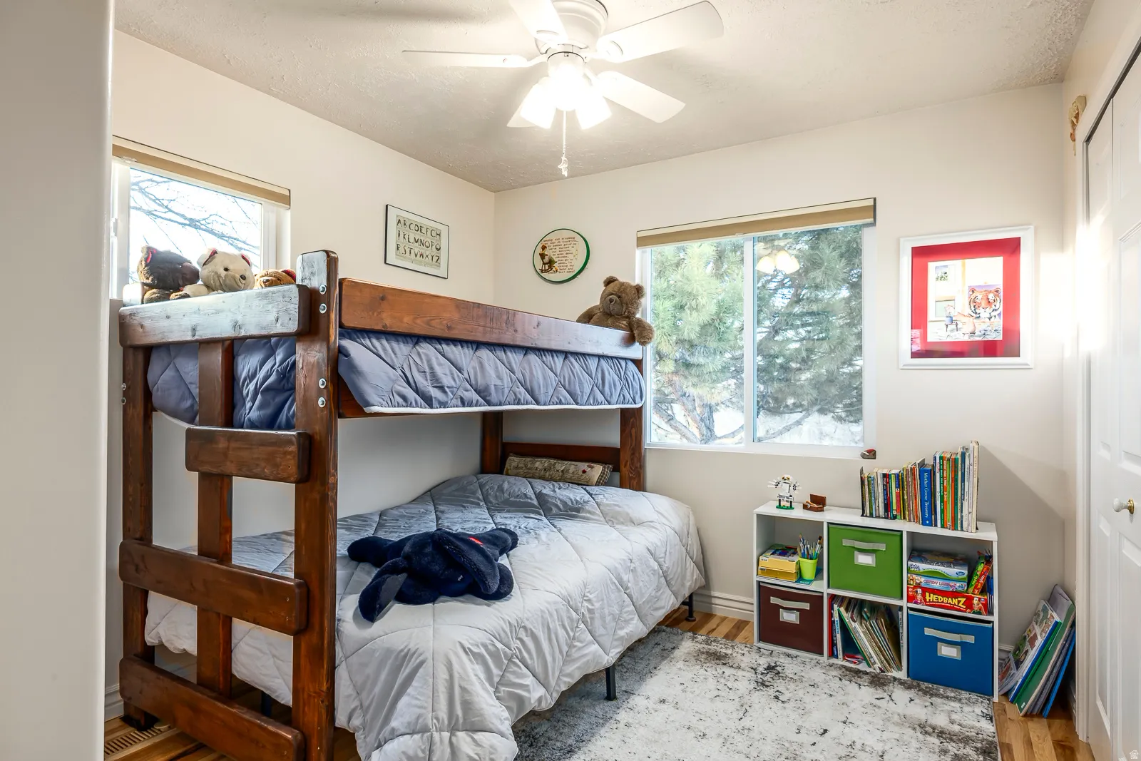 Light-filled room featuring two large windows, a ceiling fan, and wood-finish flooring