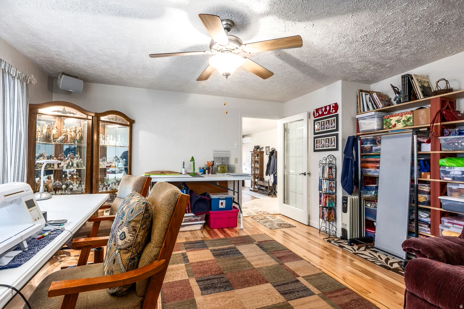 Hardwood-finish flooring featuring a ceiling fan with integrated lighting, built-in shelving, and a paneled interior door