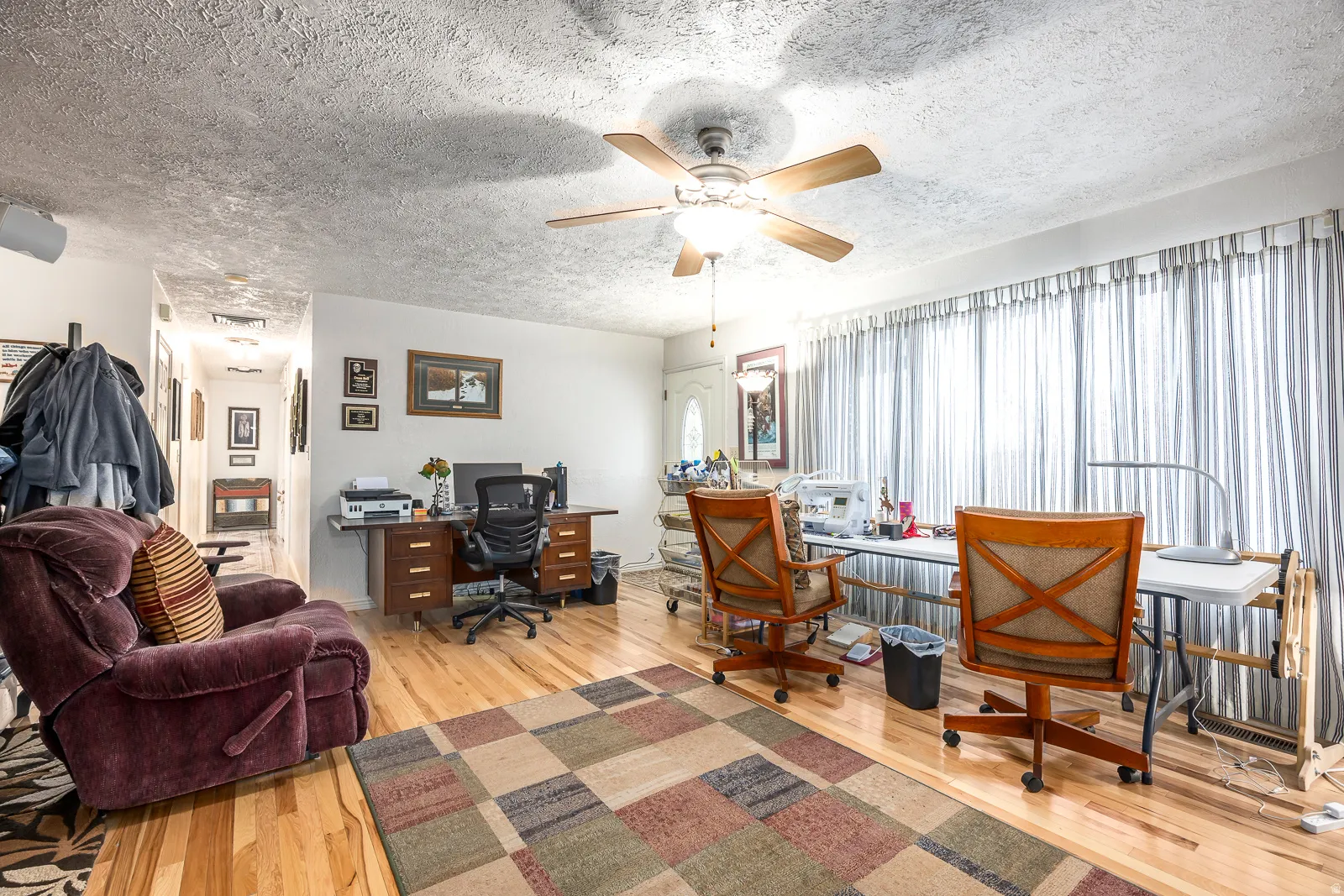 Spacious room featuring wood-finish flooring, a ceiling fan, and white walls