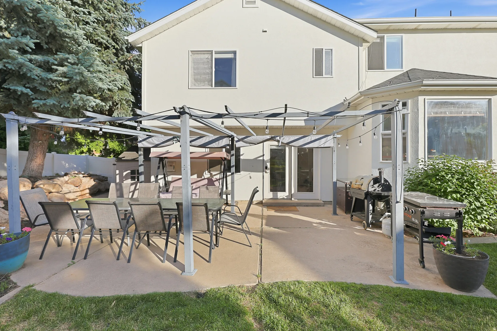 Expansive concrete patio featuring a pergola structure with string lighting