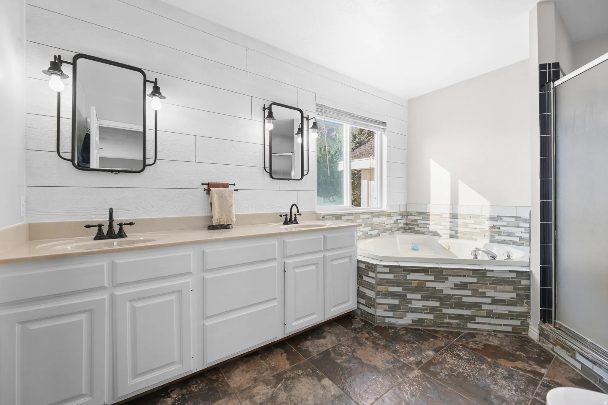 Dual sink vanity with light-toned countertops, white cabinetry, and matte black fixtures