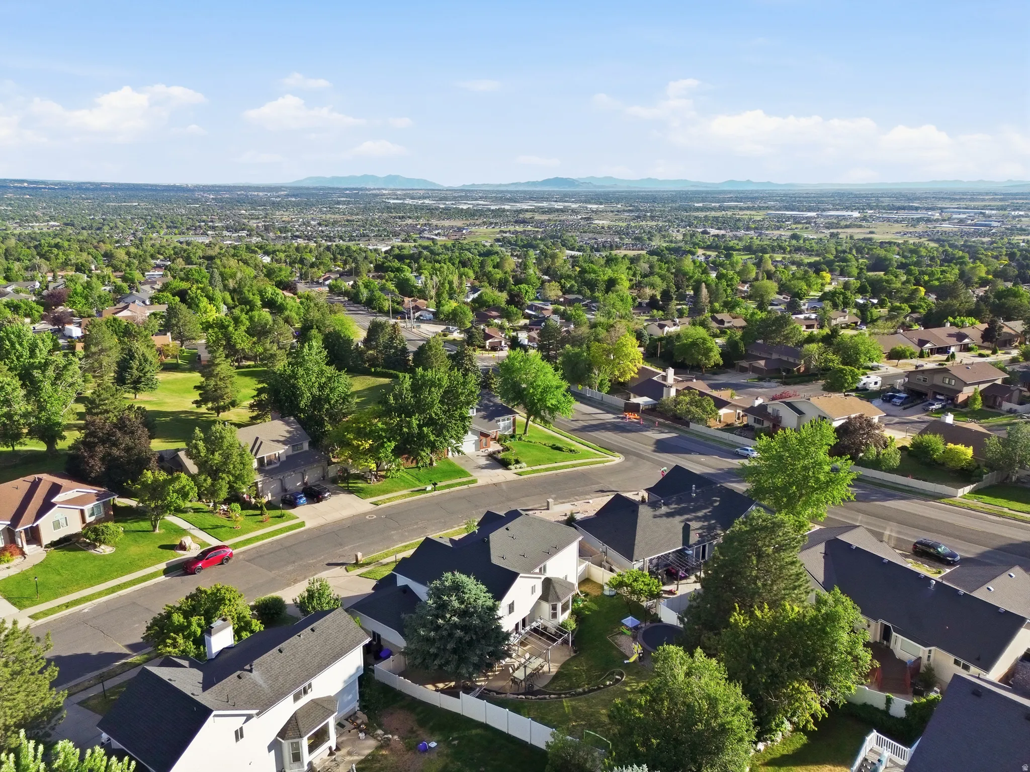 Expansive residential area featuring established homes with dark shingle roofs, mature trees, and green lawns