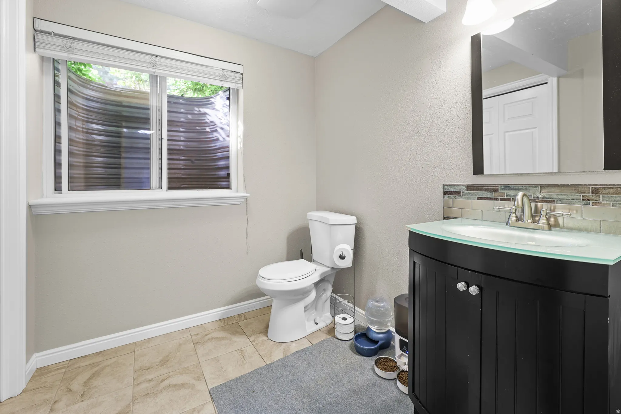 Modern vanity with a clear glass countertop, undermount sink, and brushed nickel faucet