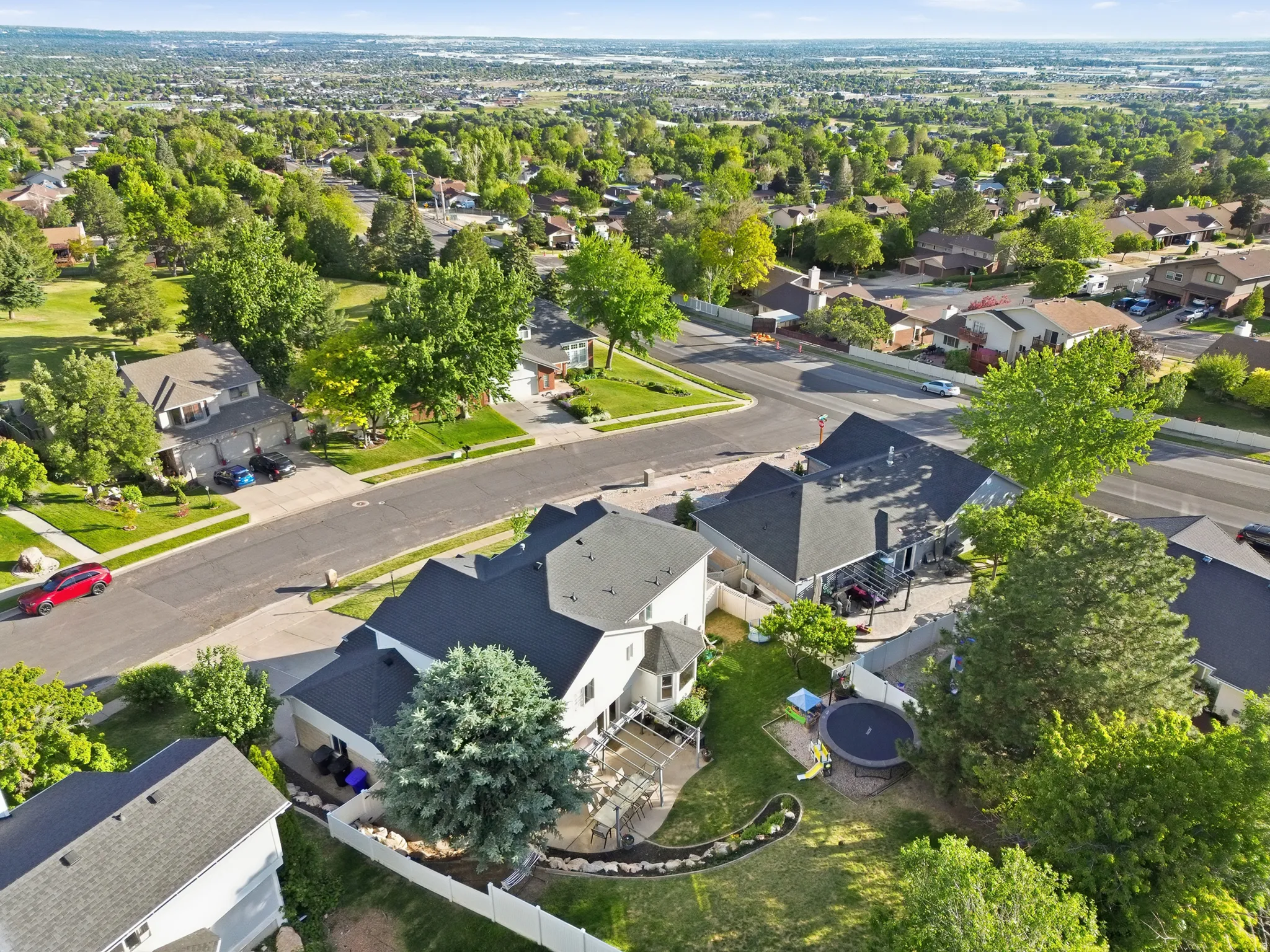 Aerial perspective showcasing a suburban neighborhood with mature trees and a residential street